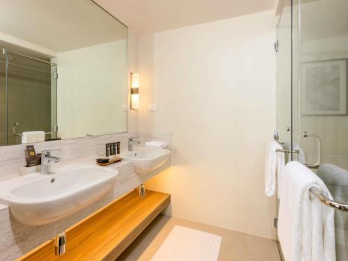 a bathroom with two sinks and a mirror at Novotel Suites Manila at Acqua in Manila