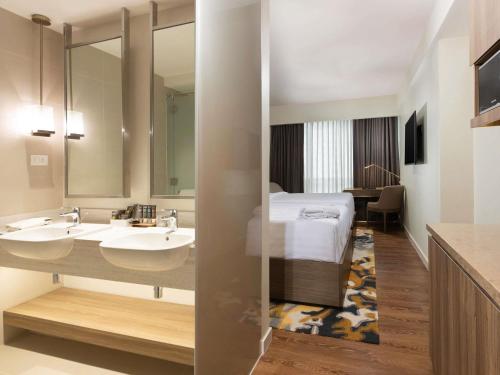 a hotel bathroom with two sinks and a bed at Novotel Suites Manila at Acqua in Manila