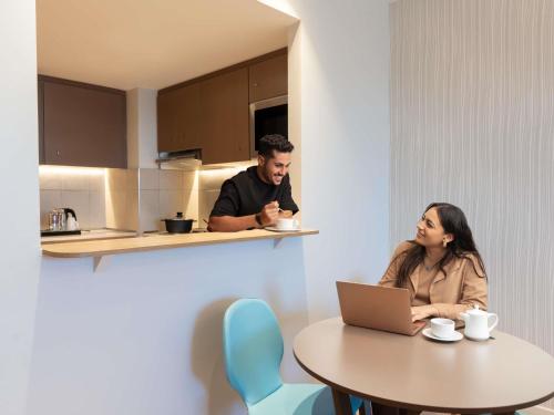 a man and a woman sitting at a table with a laptop at Adagio Jeddah City Center in Jeddah