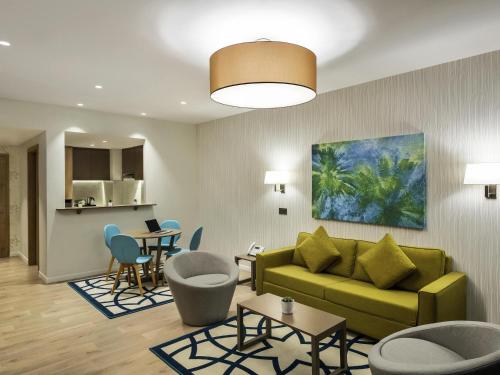 a living room with a green couch and a table at Adagio Jeddah City Center in Jeddah