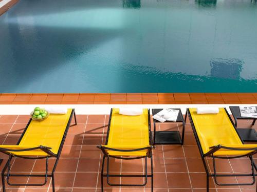 a pool with two chairs and a table with fruit on it at Adagio Jeddah City Center in Jeddah