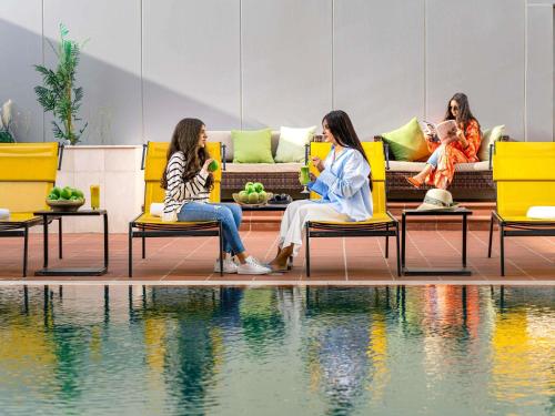 a group of women sitting on chairs next to a pool at Adagio Jeddah City Center in Jeddah