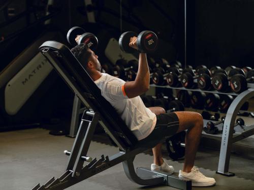 a man sitting in a gym lifting weights at Adagio Jeddah City Center in Jeddah