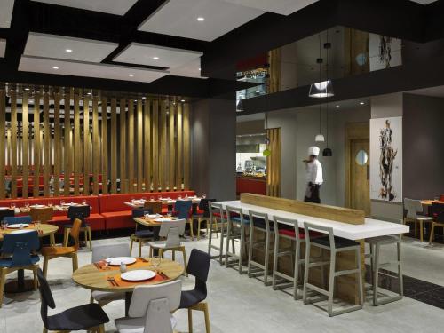 a restaurant with tables and chairs and a chef in the background at Adagio Jeddah City Center in Jeddah