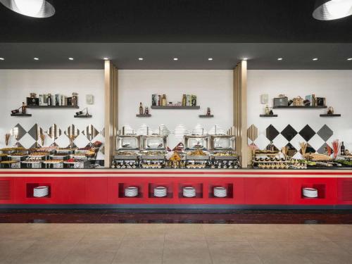 a store with a red counter with bowls and plates at Adagio Jeddah City Center in Jeddah