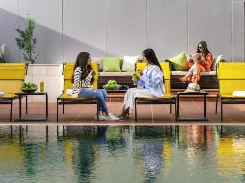 a group of women sitting on chairs next to a pool at Adagio Jeddah City Center in Jeddah