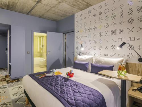 a bedroom with a large bed with purple sheets at ibis Styles Bucharest City Center in Bucharest