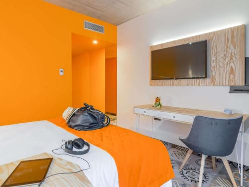 a room with a bed with a desk and a television at ibis Styles Bucharest City Center in Bucharest