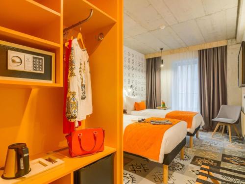 a hotel room with two beds with orange walls at ibis Styles Bucharest City Center in Bucharest