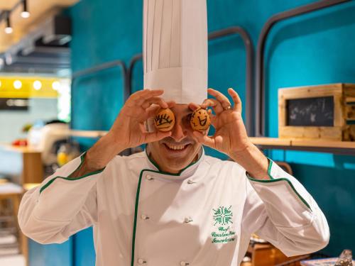 a chef holding up a stack of food on his eyes at ibis Styles Bucharest City Center in Bucharest