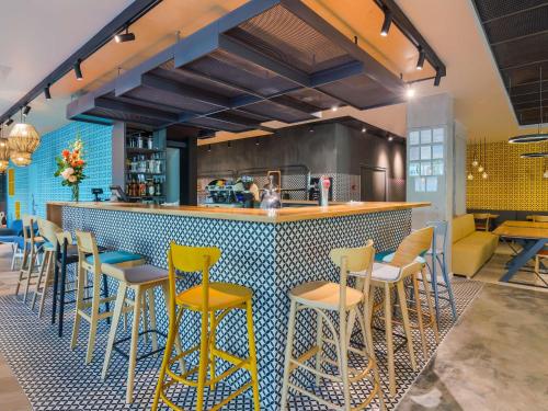 a restaurant with a bar with yellow stools at ibis Styles Bucharest City Center in Bucharest