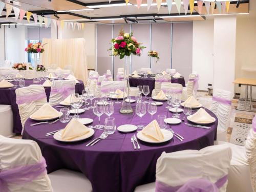 a table with purple table cloths and napkins on it at ibis Styles Bucharest City Center in Bucharest