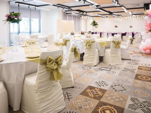 a banquet hall with white tables and chairs with bows at ibis Styles Bucharest City Center in Bucharest
