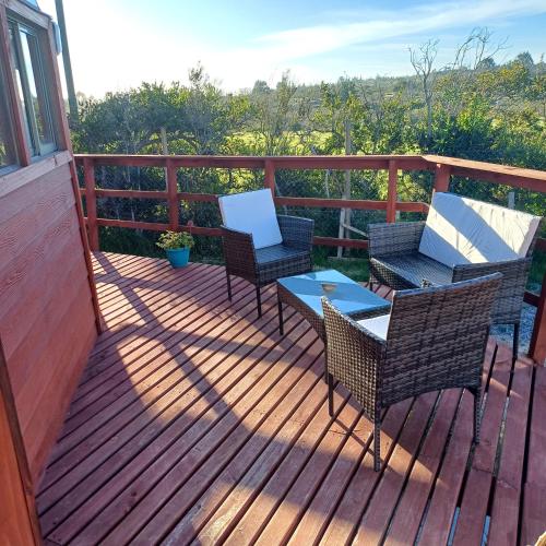 a wooden deck with chairs and a table and a laptop at Domo Tunquen in Tunquen