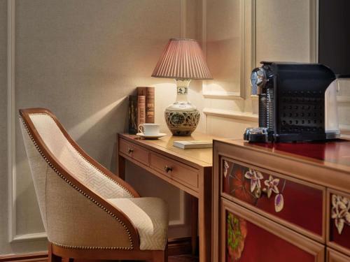 a desk with a chair and a lamp on top of it at Grand Mercure Hanoi in Hanoi