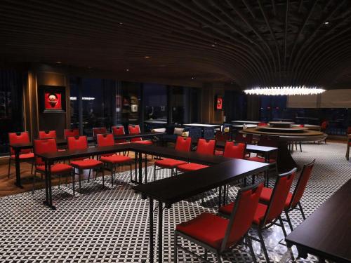 a dining room with tables and red chairs at Grand Mercure Hanoi in Hanoi