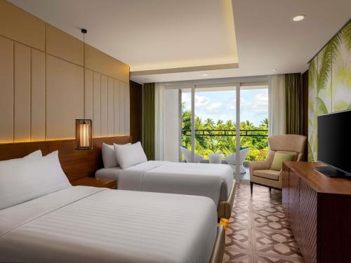 a hotel room with two beds and a television at Movenpick Resort & Spa Boracay in Boracay