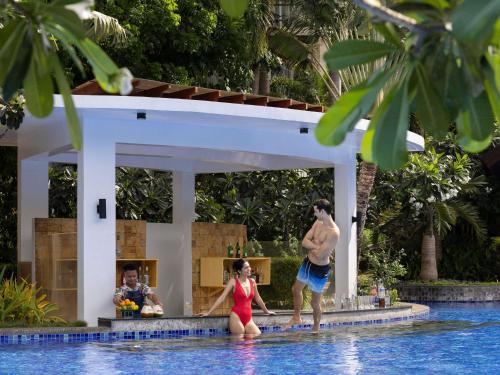 a man and a woman standing in the water in a swimming pool at Movenpick Resort & Spa Boracay in Boracay