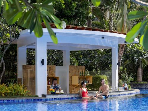 a group of people sitting in the water in a swimming pool at Movenpick Resort & Spa Boracay in Boracay
