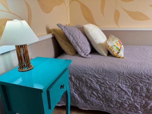 a bed with a blue night stand next to a lamp at Paraíso na praia 800 mts do mar in Imbé
