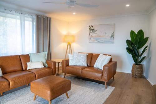 a living room with two leather couches and a plant at Ocean Daze in Woolgoolga