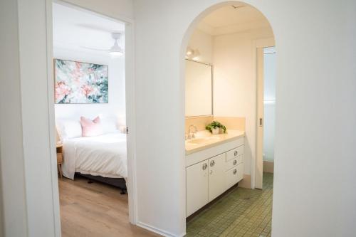 a bathroom with a sink and a bed with a mirror at Ocean Daze in Woolgoolga