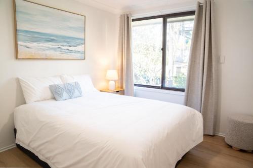 a white bedroom with a large bed and a window at Ocean Daze in Woolgoolga