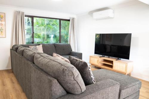 a living room with a couch and a flat screen tv at Ocean Daze in Woolgoolga