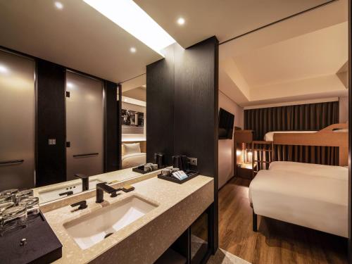 a bathroom with a sink and a bed in a room at Mercure Ambassador Seoul Hongdae in Seoul