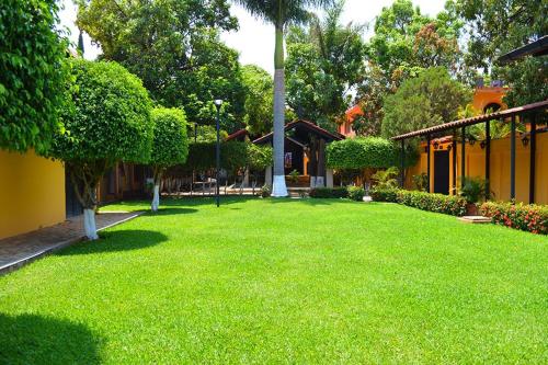 a yard with green grass and trees and a building at Casa Kolping in Tuxtla Gutiérrez