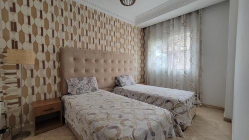 a bedroom with two beds and a window at Résidence jawharat mogador in Essaouira