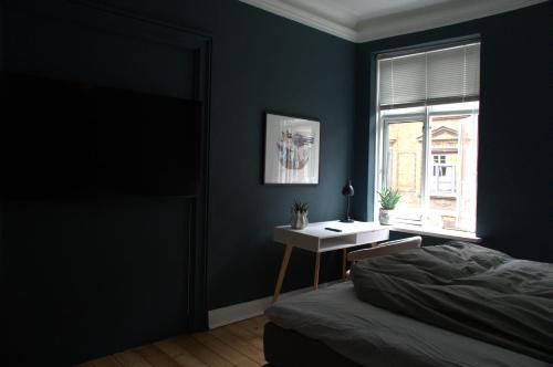a bedroom with a bed and a desk and a window at Green Brook - Blue Suite in Aalborg