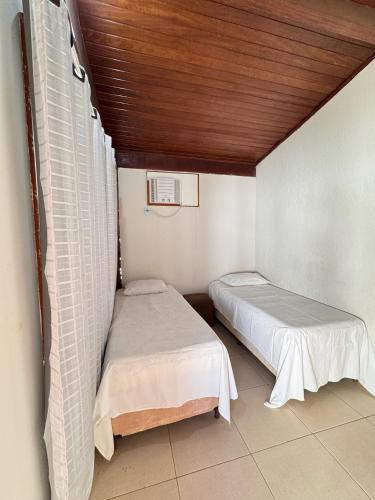 two beds in a small room with a wooden ceiling at Hotel pousada Janaúba in Janaúba
