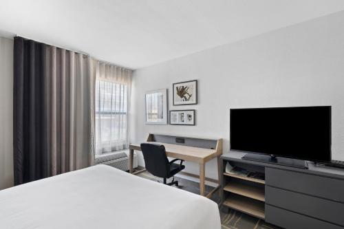 a hotel room with a bed and a flat screen tv at GreenTree Inn & Suites Phoenix Sky Harbor in Phoenix