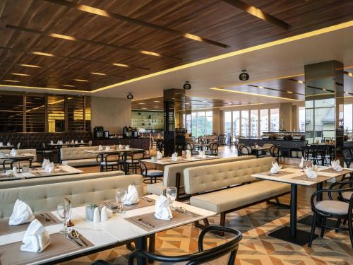 a dining room with tables and chairs and a restaurant at Mercure Langkawi Pantai Cenang in Pantai Cenang