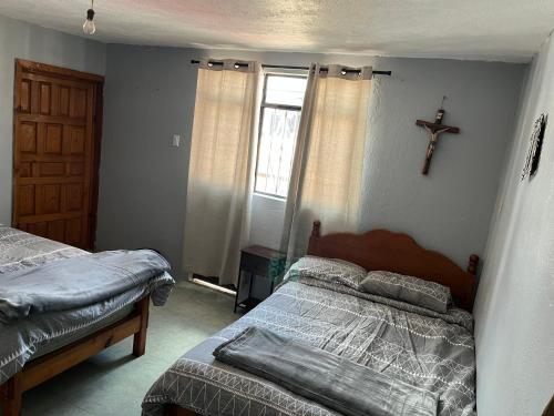 a bedroom with two beds and a cross on the wall at Casa Gómez in Mazamitla