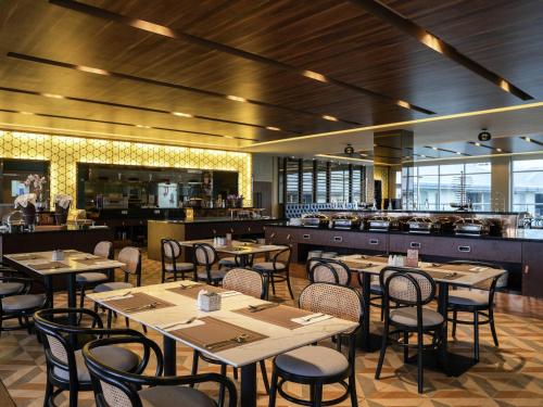 a restaurant with tables and chairs and a kitchen at Mercure Langkawi Pantai Cenang in Pantai Cenang