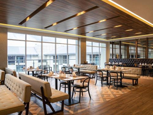 a restaurant with tables and chairs and windows at Mercure Langkawi Pantai Cenang in Pantai Cenang