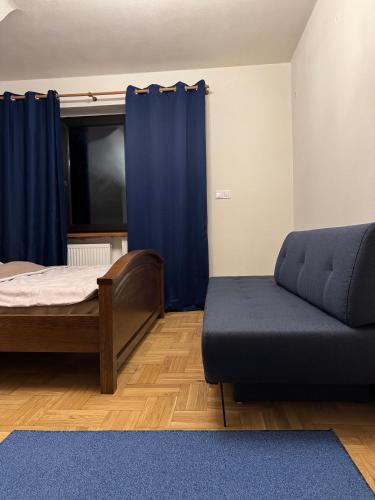 a bedroom with a bed and a couch and a window at Hotel Familiar in Kobyłka
