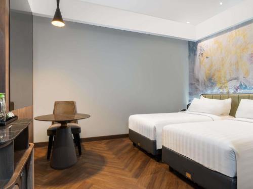 a hotel room with two beds and a table at Mercure Jayapura in Jayapura