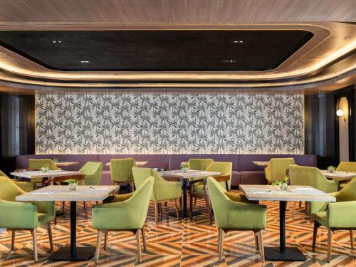 a dining room with tables and green chairs at Mercure Jayapura in Jayapura