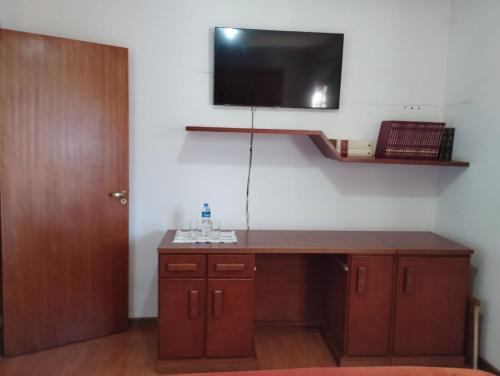 a room with a desk with a tv on the wall at Suítes Refúgio do Sossego - Campos do Jordão in Campos do Jordão