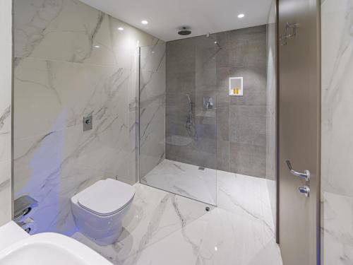 a white bathroom with a shower and a toilet at Mercure St. Julian's Malta in St Julian's