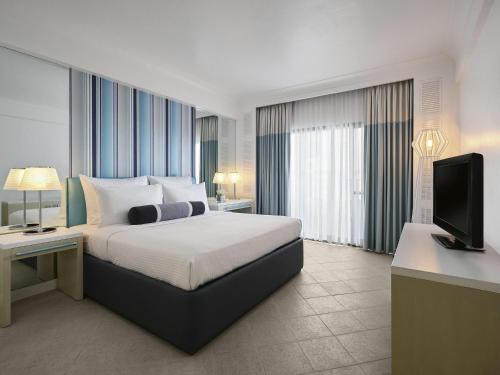 a hotel room with a bed and a television at Mövenpick Hotel Mactan Island Cebu in Mactan