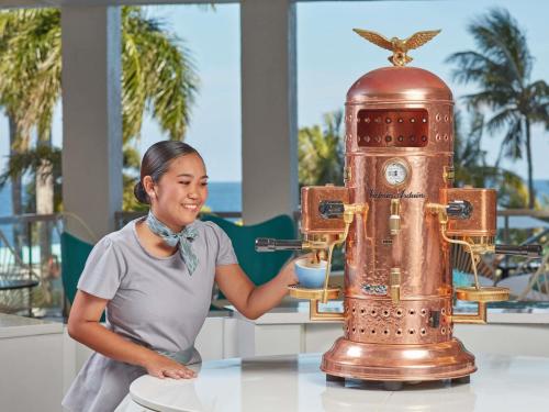 a woman is standing next to a table with a machine at Mövenpick Hotel Mactan Island Cebu in Mactan