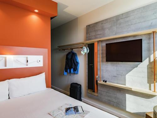 a hotel room with a bed and a flat screen tv at ibis budget Beauvais Aeroport in Beauvais