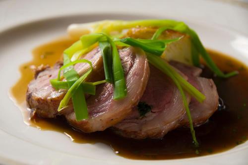 a plate of meat with sauce and green onions on it at Chateau La Chaire in Rozel