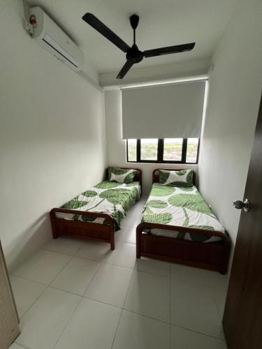 two beds in a room with a ceiling fan at I&M Staycation in Alor Setar