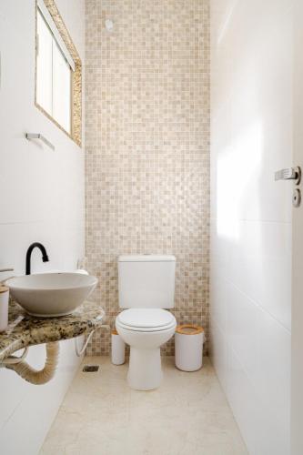 a bathroom with a white toilet and a sink at Casa espaçosa com quintal perto da lagoa in Araruama