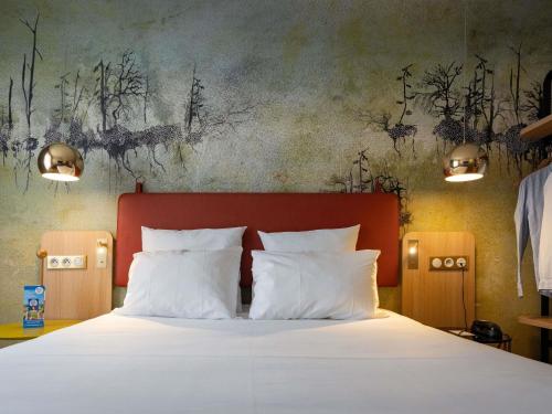 a bedroom with a large bed with white pillows at Mercure Saint Omer Centre Gare in Saint-Omer